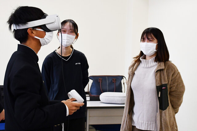 VRゴーグルをつける高校生とそれを見守る大学生の写真